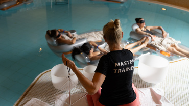 Menschen treiben auf Schwimmreifen in einem Pool während eines Klangbads.